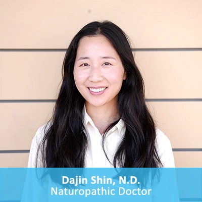 Naturopathic Doctor Dajin Shin In Front Of Wooden Wall With Caption
